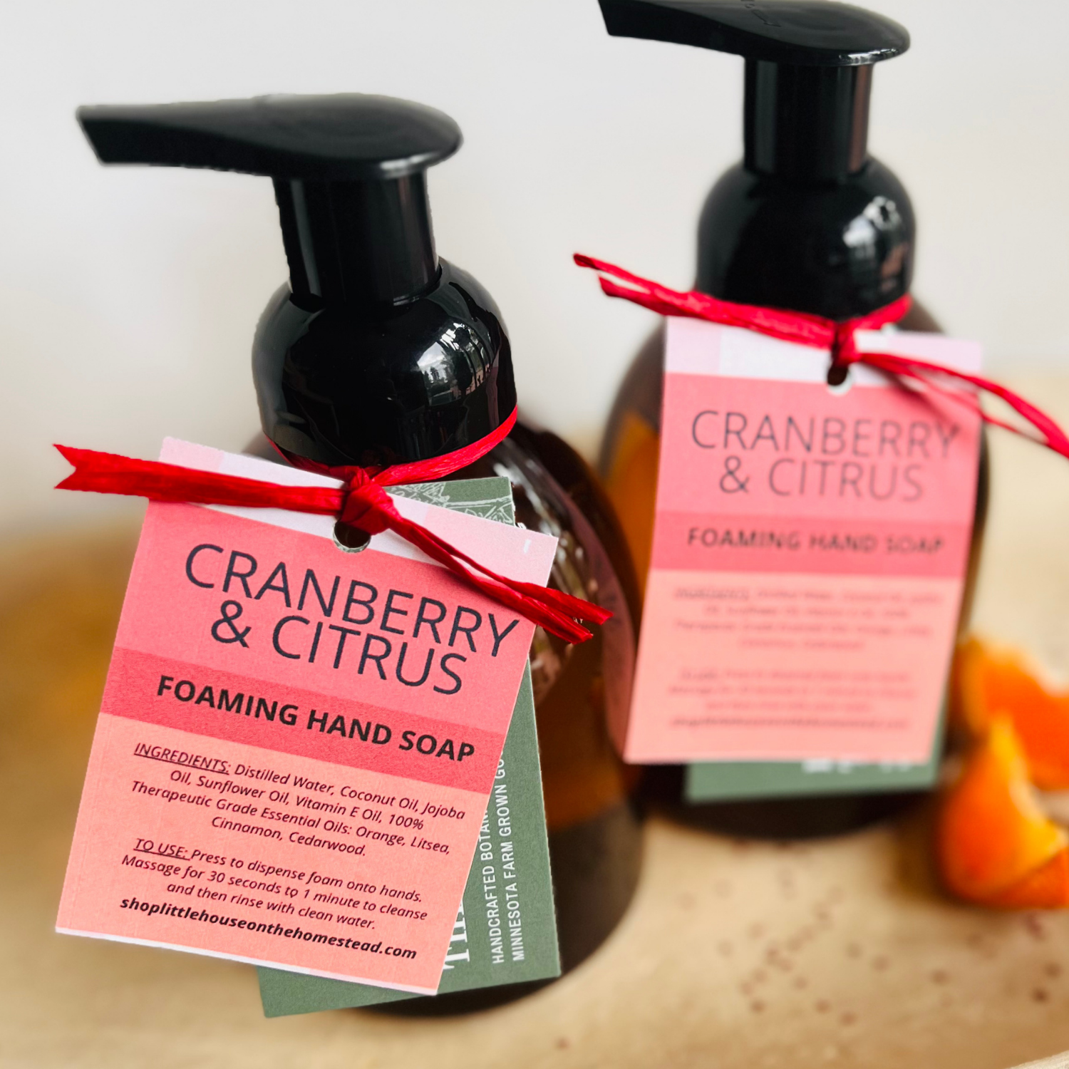 Fall Cranberry & Citrus foaming hand soap in amber bottle, with fresh orange slices laying on a ceramic tray.